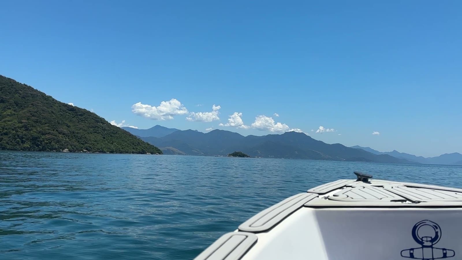 Bug eines Schnellboots auf blauem Wasser, dahinter bewaldete Hügel und die Berge der Küste